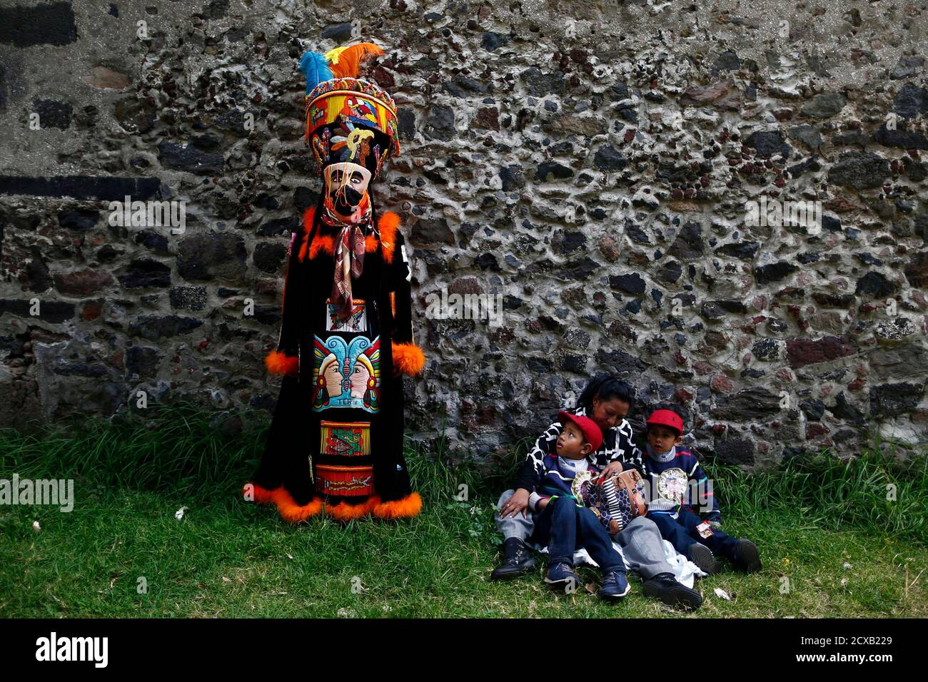 A boy sitting with his family looks up at a traditional Chinelo costumed  dancer during a celebration 40 days after the birth of Jesus, in Xochimilco  on the outskirts of Mexico City,