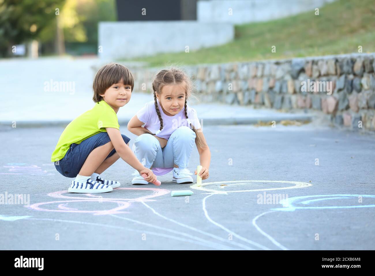 Little children drawing with chalk on asphalt Stock Photo - Alamy