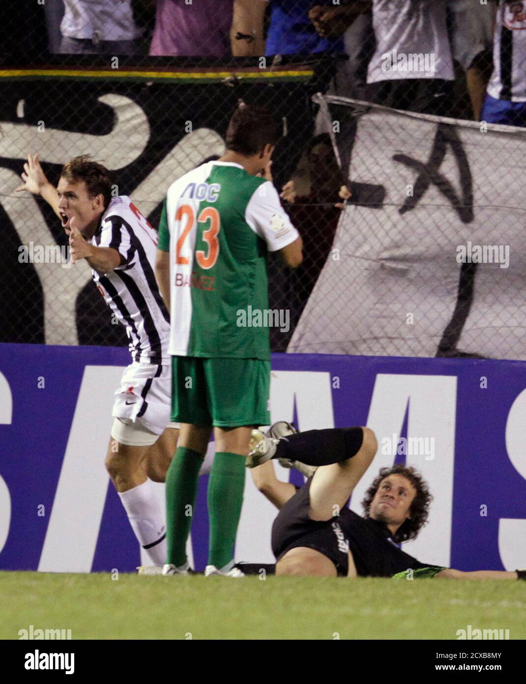 Luciano Civelli (L) of Paraguay's Libertad celebrates his goal against  Peru's Alianza de Lima Walter Ibanez (23) and goalkeeper Salomon Libman  during their Copa Libertadores soccer match in Asuncion, February 9, 2012.