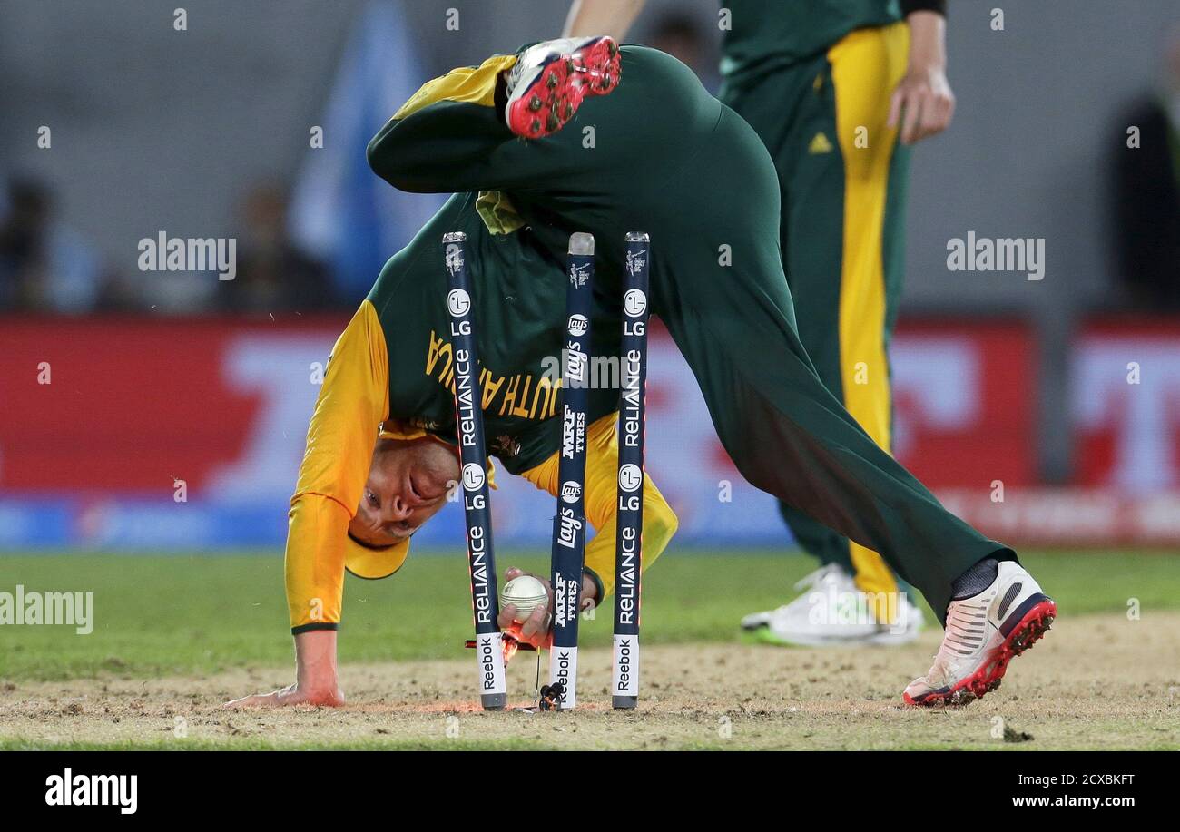 South Africa's captain AB de Villiers tumbles over the stumps during a  failed run out attempt on New Zealand's batsman Corey Anderson during their  Cricket World Cup semi-final match in Auckland, March