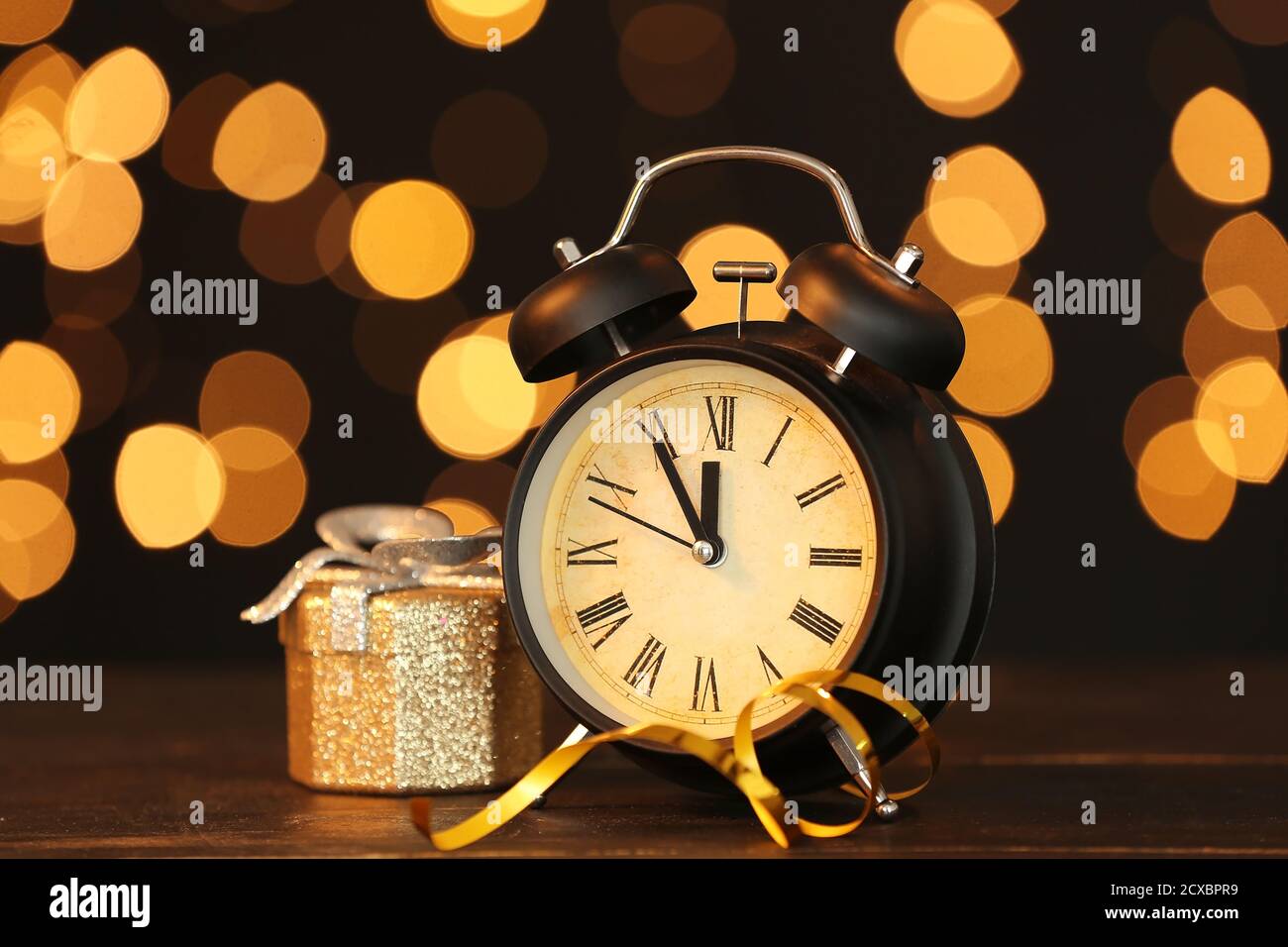 Alarm clock and Christmas gift against blurred lights Stock Photo