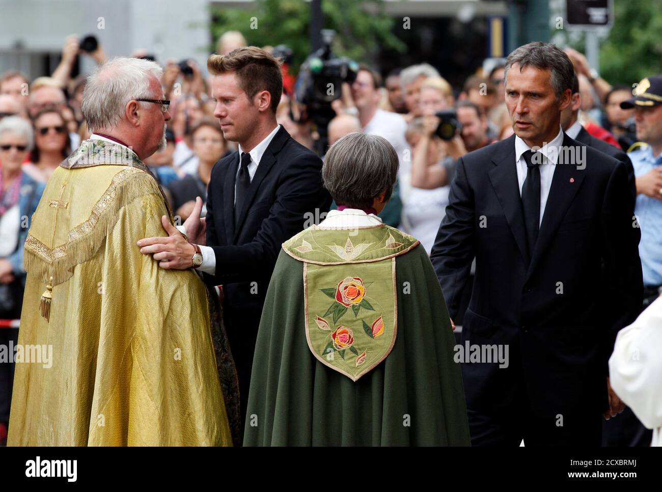 Norwegian Prime Minister Jens Stoltenberg (R) and Eskil Pedersen (2nd L), the leader of the youth wing of ruling Labour Party, are comforted by priests after a memorial service at a cathedral in Oslo, July 24, 2011.At least 92 people are dead after a gunman dressed in police uniform opened fire at a youth camp of Norway's ruling political party on Friday hours after a bomb blast in the government district in the capital Oslo. REUTERS/Wolfgang Rattay (NORWAY - Tags: CIVIL UNREST CRIME LAW POLITICS RELIGION) Stock Photo