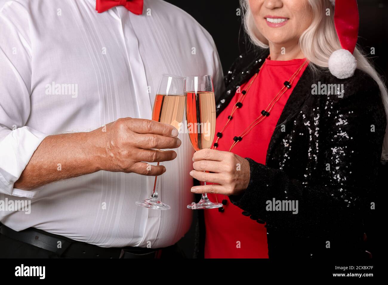 Elderly couple with champagne on dark background. New Year celebration Stock Photo