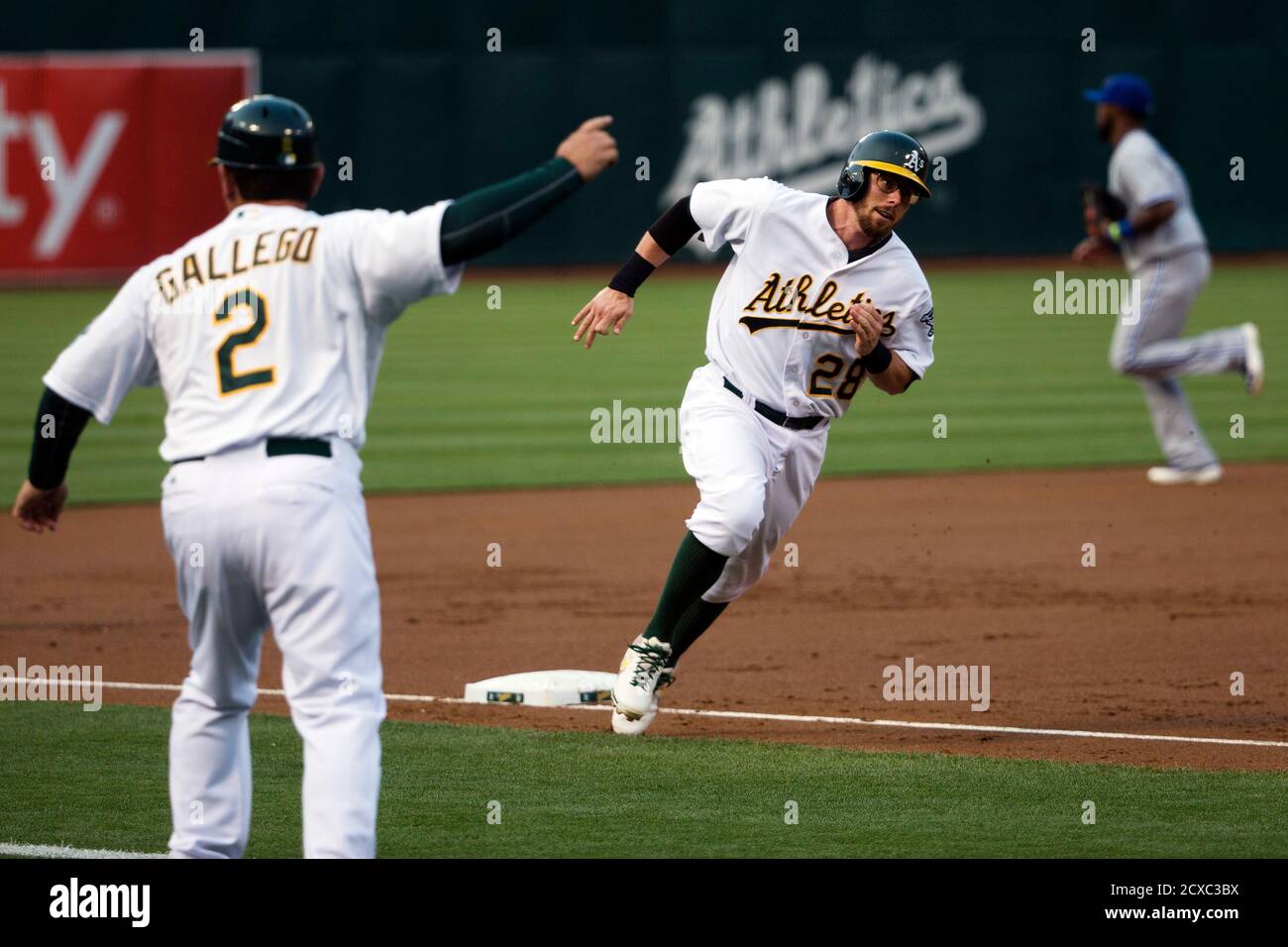 Oakland Athletics' third base coach Mike Gallego (2) signals baserunner  Eric Sogard (28) to round home during the first inning of their MLB  American League game against the Toronto Blue Jays at