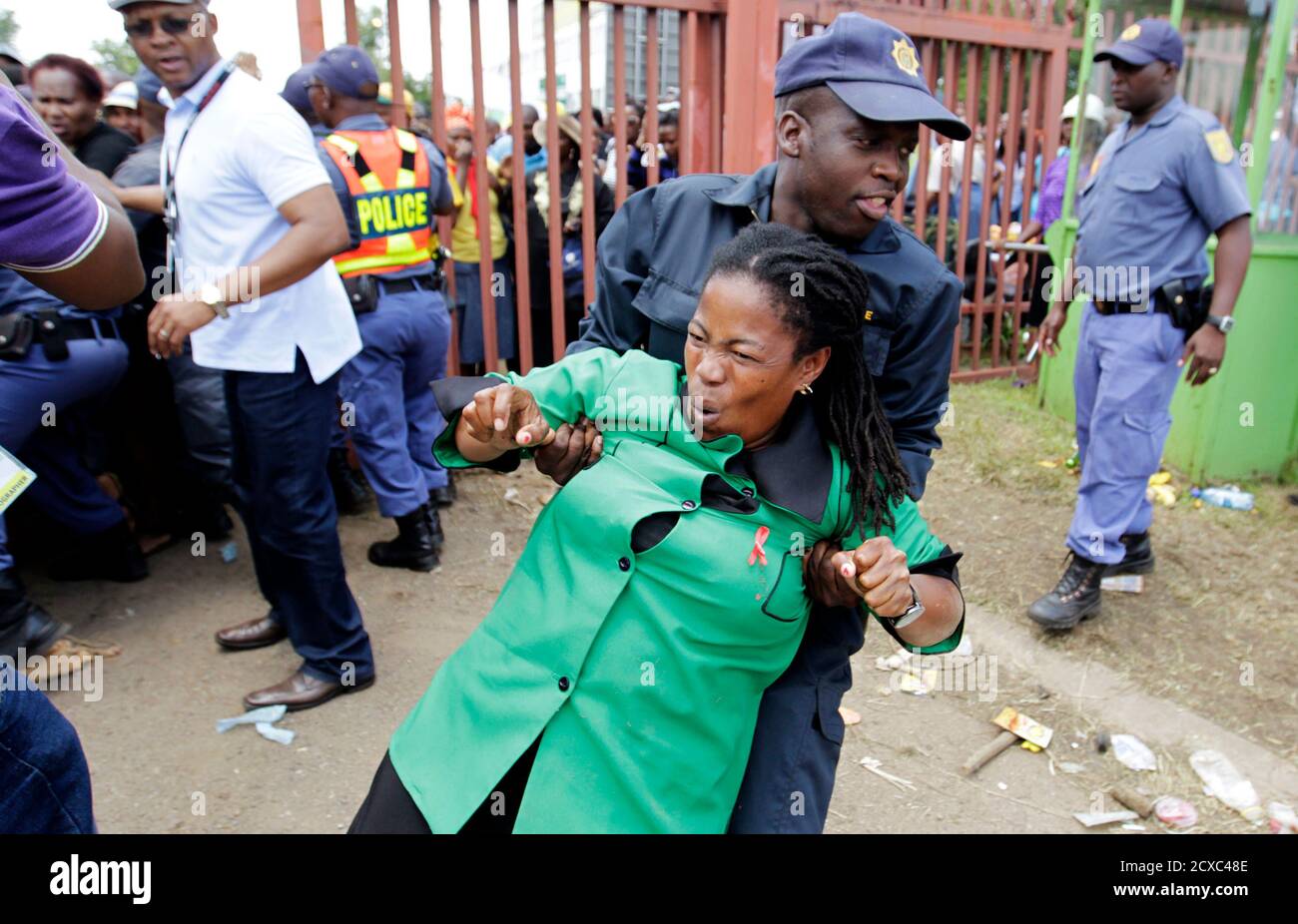 A policeman assists a mourner who fell during a stampede while running to queue before boarding a bus to take her to the Union Buildings, where former South African President Nelson Mandela is lying in state, in Pretoria December 13, 2013. REUTERS/Thomas Mukoya (SOUTH AFRICA - Tags: OBITUARY POLITICS TPX IMAGES OF THE DAY) Stock Photo