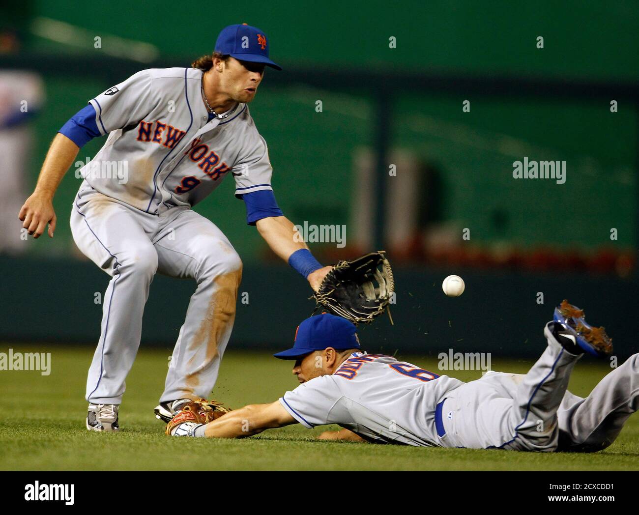 New York Mets left fielder Kirk Nieuwenhuis (L) attempts to field a  Washington Nationals Bryce Harper (not in photo) bloop single while  avoiding teammate and shortstop Omar Quintanilla (R) in the seventh