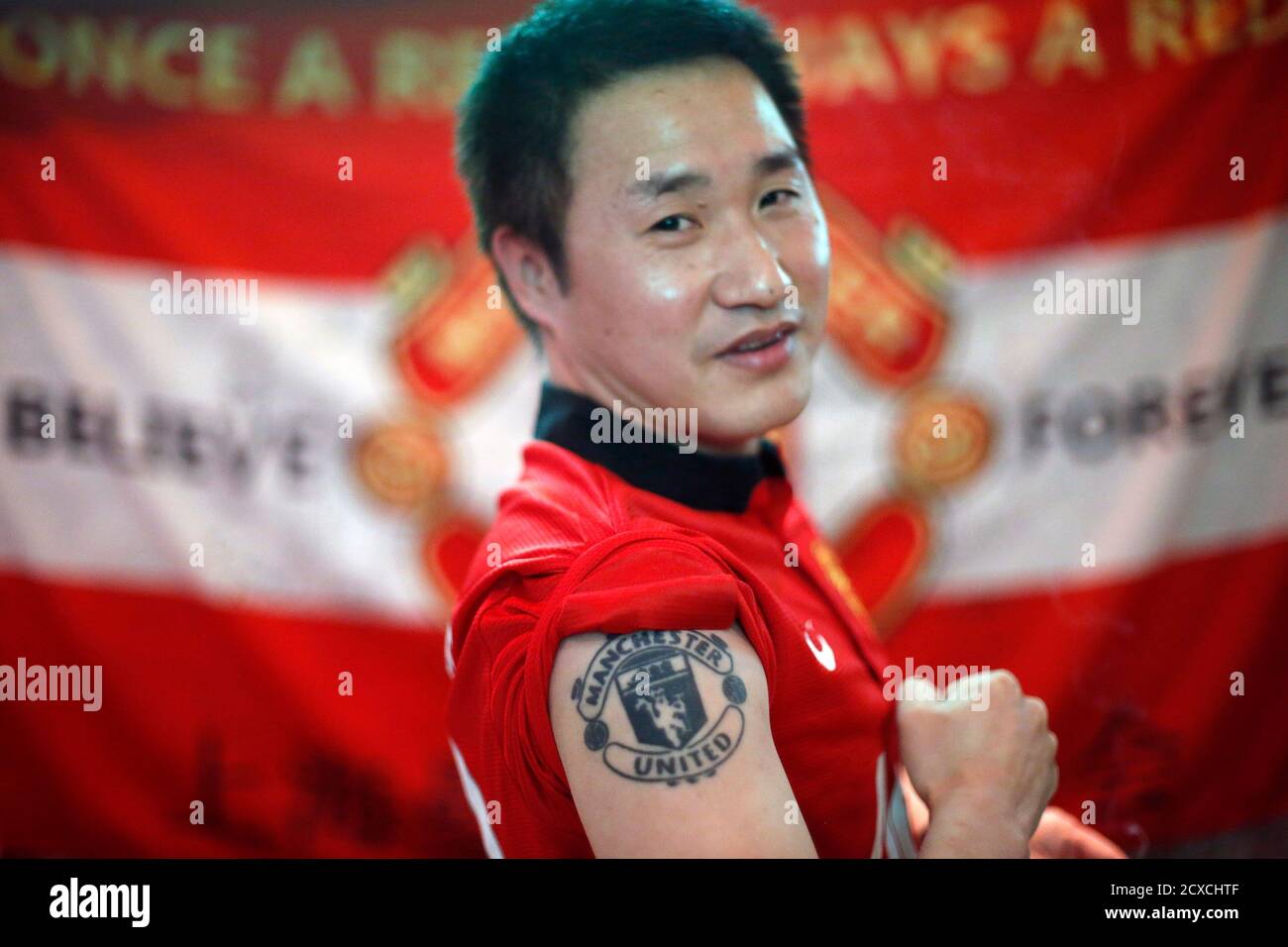 A fan of Manchester United Shanghai fan club shows his tattoo at half-time during a telecast of the team's English Premier League soccer match against Fulham at a bar in Shanghai February 10, 2014. REUTERS/Aly Song (CHINA - Tags: SOCIETY SPORT SOCCER) Stock Photo