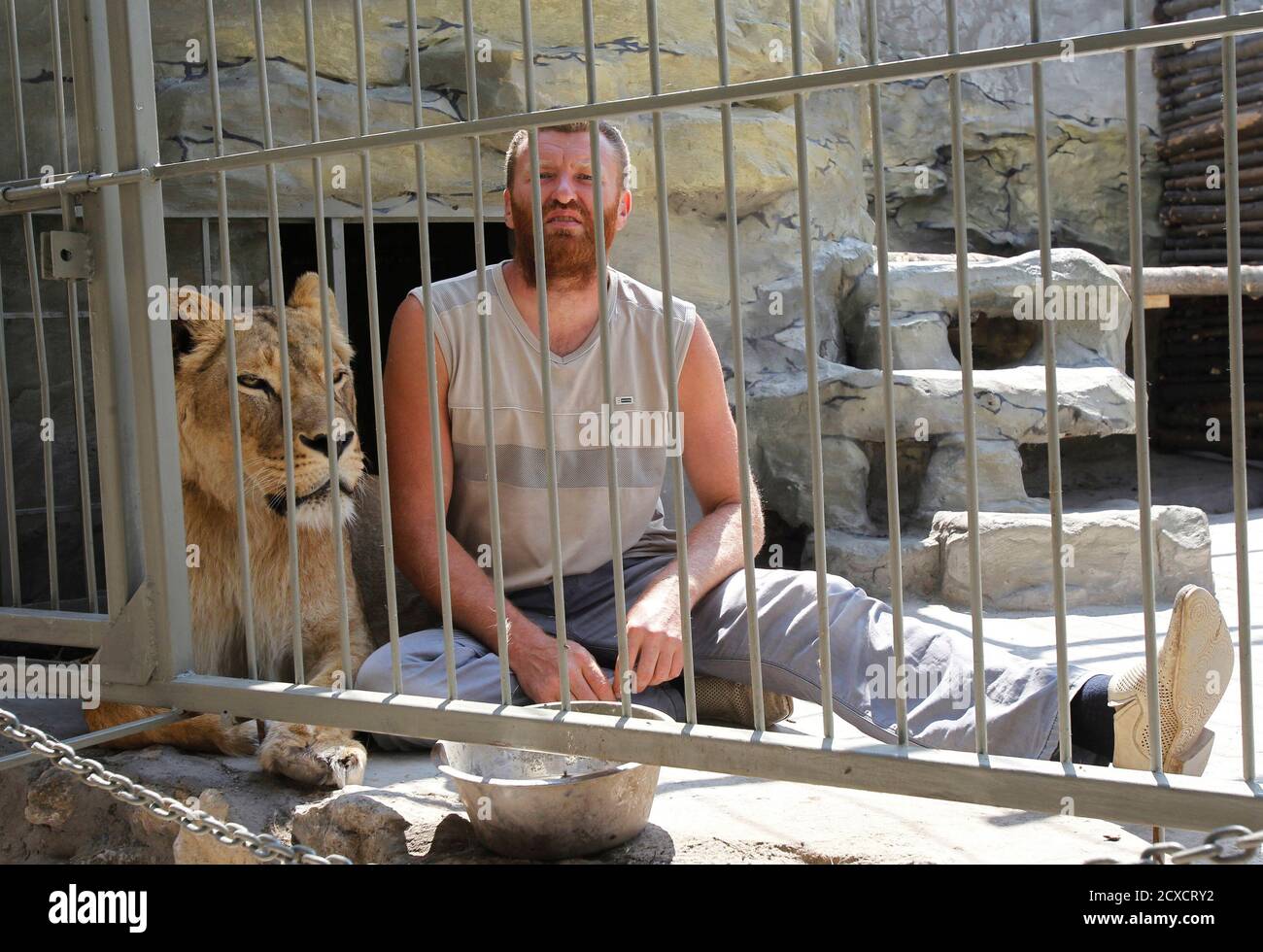 Zoo owner and artist Aleksandr Pylyshenko sits inside a cage with female  African lion Katya at a private zoo situated in his yard in the city of  Vasilyevka, southeastern Ukraine August 3,