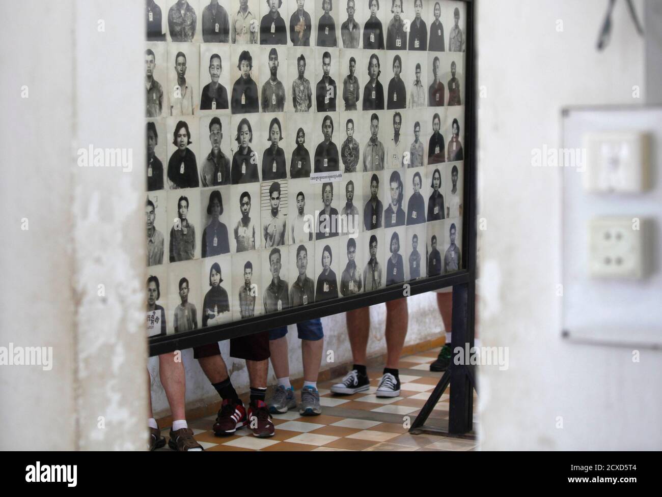 Tourists are seen near photographs of Khmer Rouge victims at the Tuol Sleng Genocide Museum, also known as the notorious security prison S-21, in Phnom Penh January 21, 2015. The U.N backed tribunal in Cambodia on Wednesday commenced the second phase of a hearing of two former top Khmer Rouge leaders, head of state Khieu Samphan and ''Brother Number Two'' Nuon Chea, on charges of genocide against the ethnic Chams and the Vietnamese. REUTERS/Samrang Pring (CAMBODIA - Tags: CRIME LAW TRAVEL POLITICS CIVIL UNREST) Stock Photo