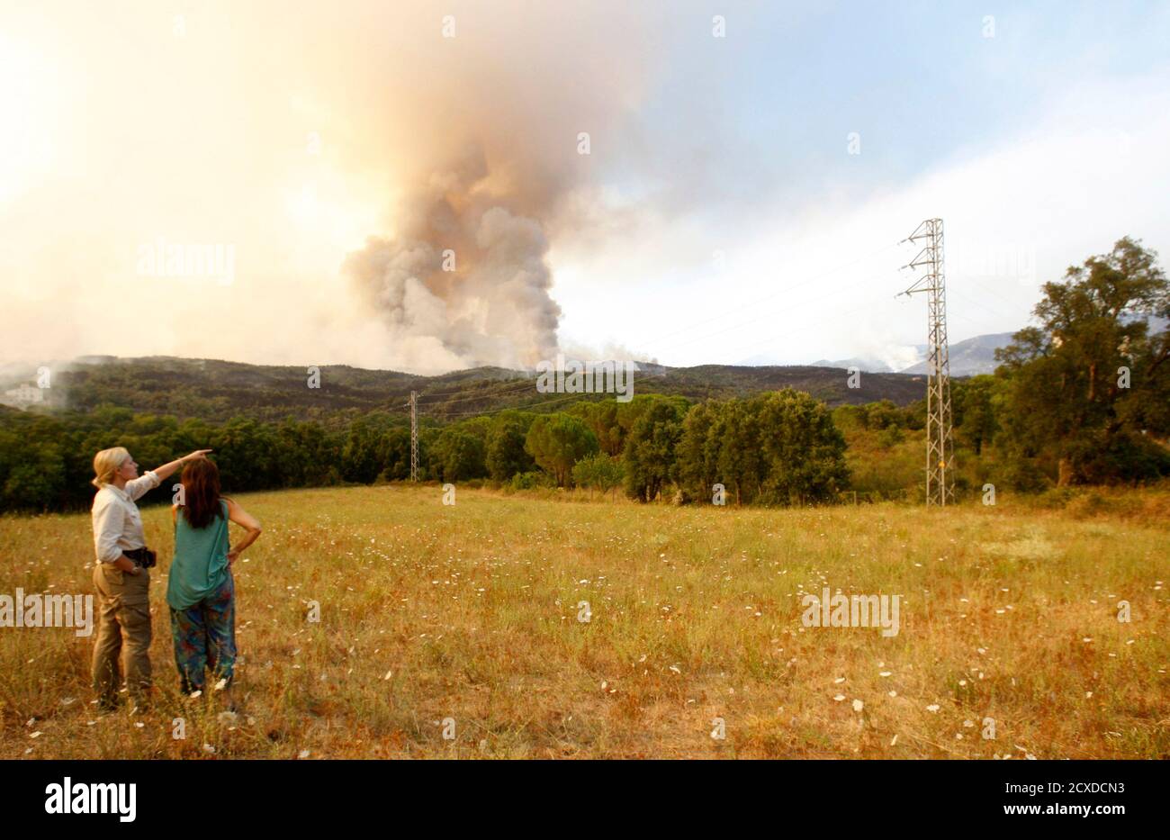 People point to the smoke near Agullana town in the Spanish province of Girona, July 23, 2012. Two big forest fires raging in the border area between France and northern Catalonia in Spain since Sunday have killed a fourth person, local authorities said on Monday, as strong winds hindered efforts to control the blaze. REUTERS/Albert Gea (SPAIN - Tags: DISASTER ENVIRONMENT) Stock Photo