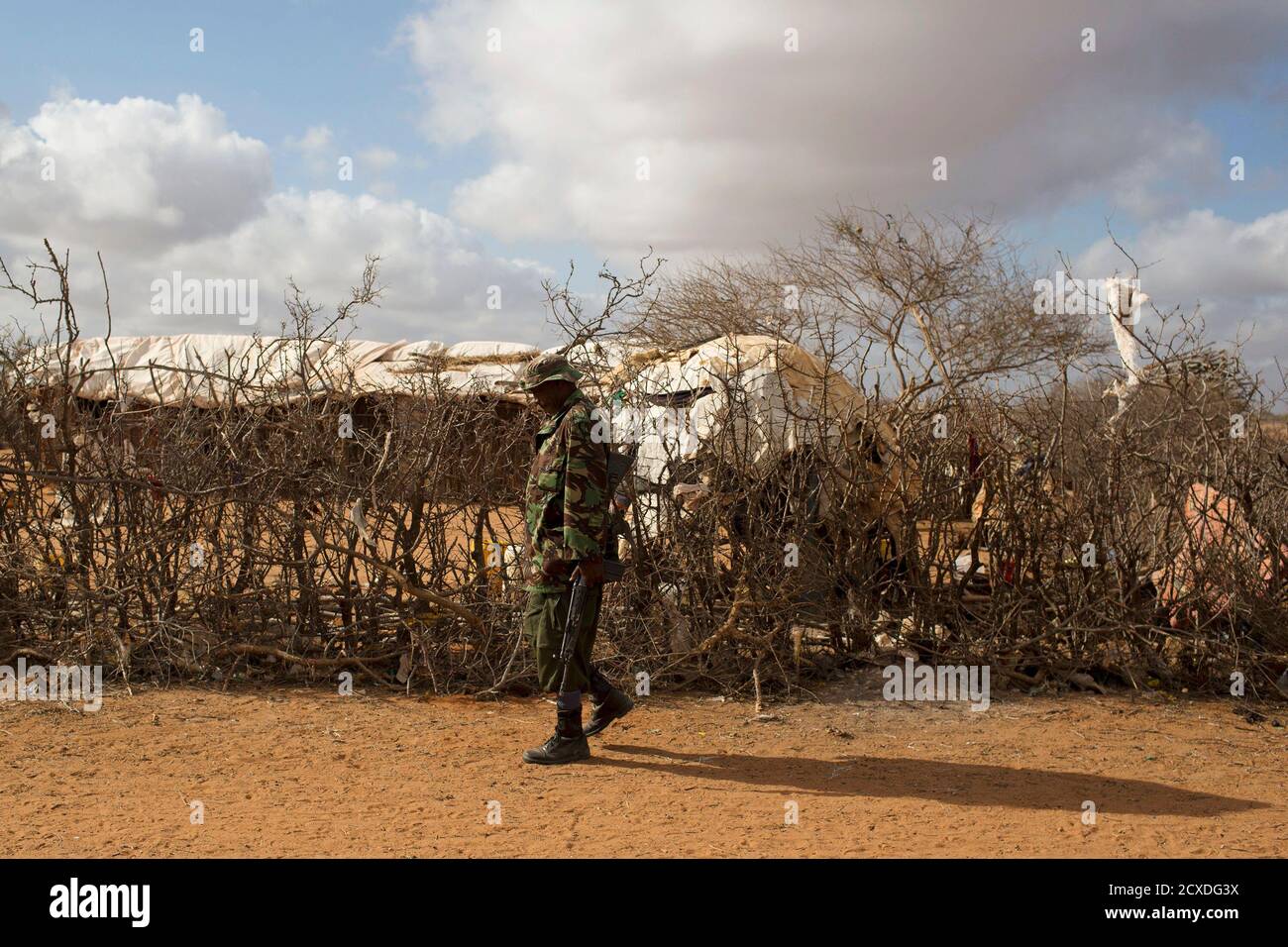 An administration police officer walks past a refugee compound at an extension of the Ifo camp, one of several refugee settlements in Dadaab, Garissa County, northeastern Kenya October 9, 2013.  REUTERS/Siegfried Modola  (KENYA - Tags: SOCIETY MILITARY) Stock Photo