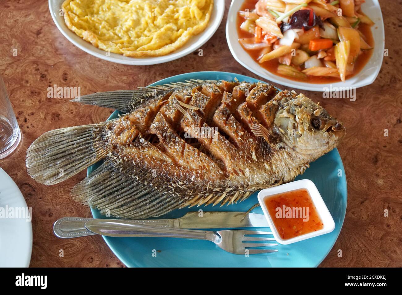 Fried whole fish in Thailand with cutlery and dipping sauce Stock Photo