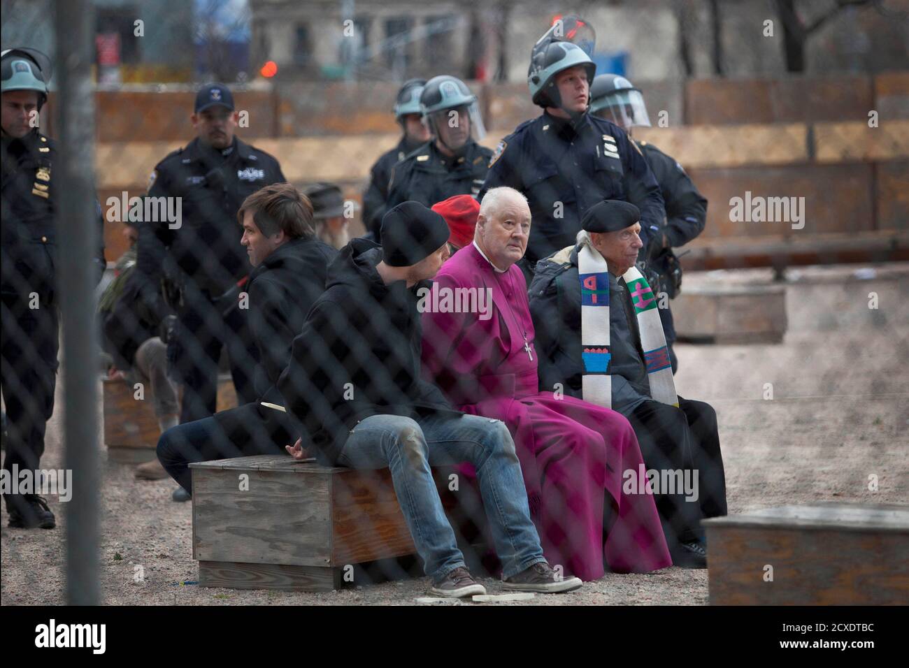 Retired Episcopal bishop George E. Packard (purple robe) and other protesters affiliated with the Occupy Wall Street movement are detained after climbing a ladder to illegally trespass on a privately-owned piece of land near Juan Pablo Duarte Square during a march in New York December 17, 2011. Hundreds of anti-Wall Street protesters took to the New York streets on Saturday in an attempt to establish a new encampment, with a number arrested as they tried to move onto church-owned land. REUTERS/Andrew Burton (UNITED STATES - Tags: CIVIL UNREST POLITICS BUSINESS RELIGION CRIME LAW) Stock Photo