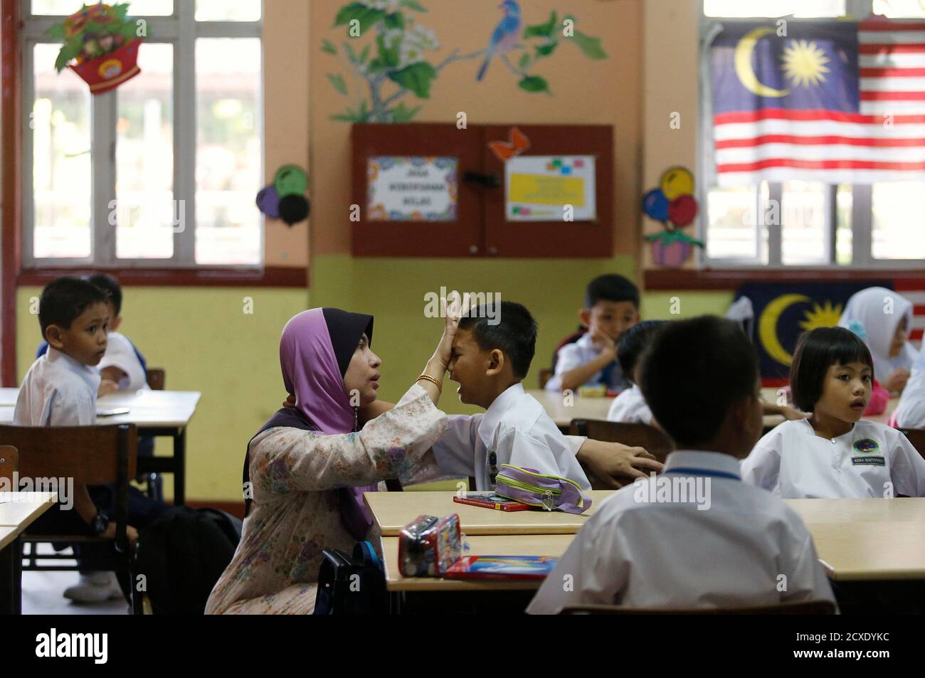 Preschooler Muhammad Ikram Suhimi, 6, is comforted by his mother 