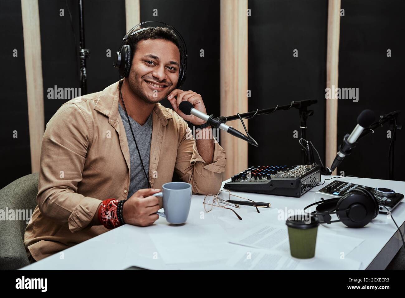 Portrait of happy young male radio host having a drink, smiling at camera  while moderating a live show Stock Photo - Alamy
