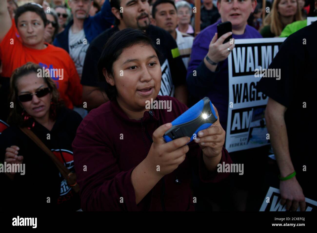 A demonstrator uses her phone as a group of protesters face arrest for civil disobedience outside Wal-Mart, during a demonstration for better wages and working conditions during Black Friday in San Leandro, California November 29, 2013. Black Friday, the day following the Thanksgiving Day holiday, has traditionally been the busiest shopping day in the United States. REUTERS/Stephen Lam (UNITED STATES - Tags: BUSINESS CIVIL UNREST) Stock Photo