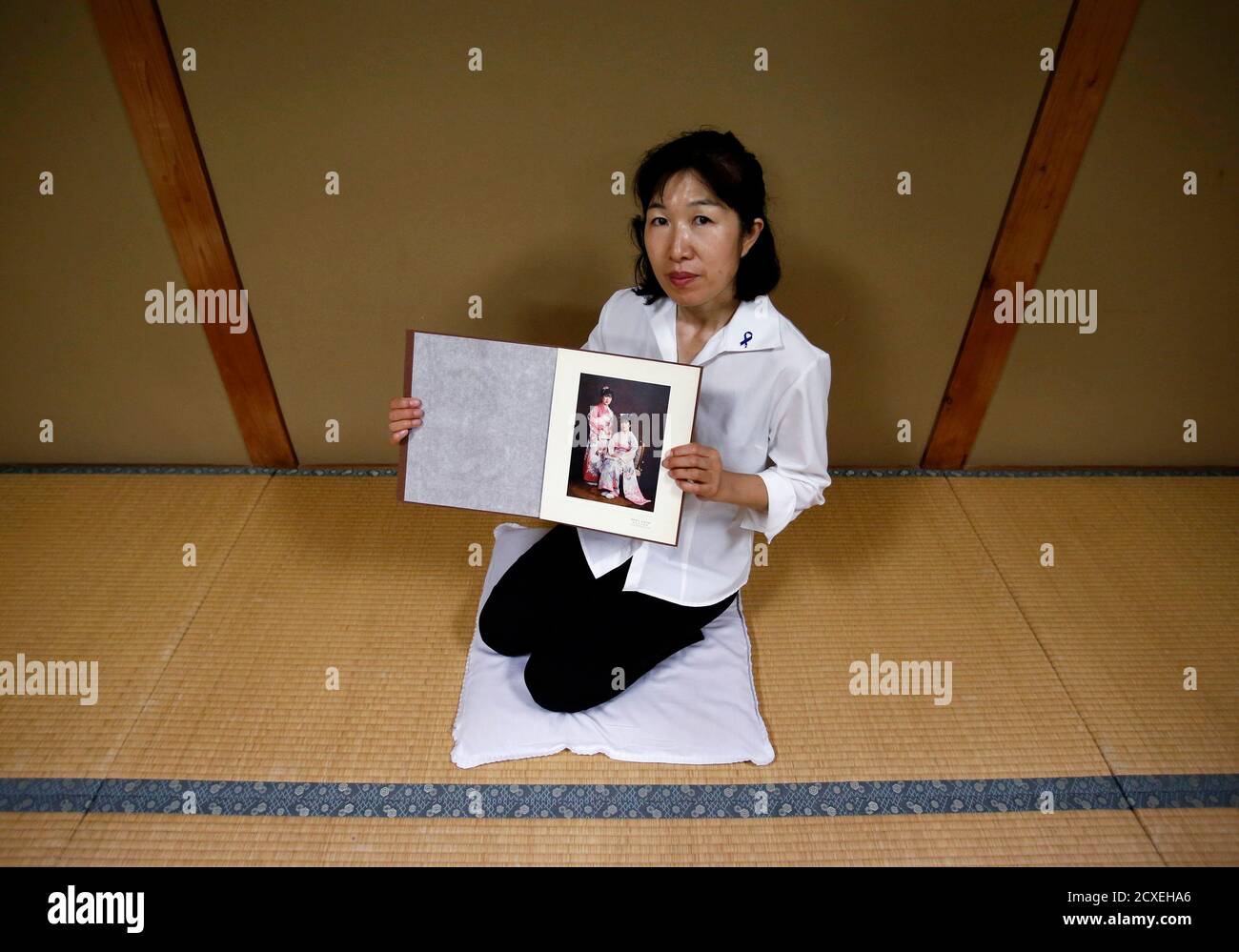 Misa Morimoto, the 50-year-old identical younger twin of Miho Yamamoto, shows a photograph of Miho and herself wearing traditional Japanese clothes known as Kimono taken to celebrate their 20th birthdays in 1984, during an interview with Reuters in Otsuki city, Yamanashi prefecture, July 15, 2014. Morimoto spoke to no one for 18 years about her identical twin sister who vanished when they were 20, not even to her own children. On the rare occasions when asked, she lied and said her sister was studying overseas. But slowly the pain of uncertainty about her sister's fate was replaced by suspicio Stock Photo