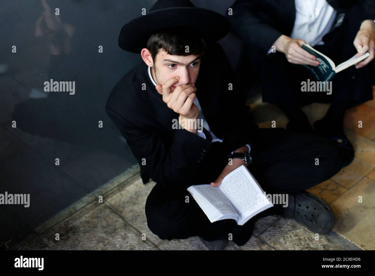 A Jewish worshipper takes part in prayers marking Tisha B'Av at the Western Wall, Judaism's holiest prayer site, in Jerusalem's Old City August 5, 2014. Tisha B'Av, a day of fasting and lament, commemorates the date in the Jewish calendar on which it is believed that First and Second Temples were destroyed in Jerusalem. REUTERS/Siegfried Modola (JERUSALEM - Tags: RELIGION) Stock Photo