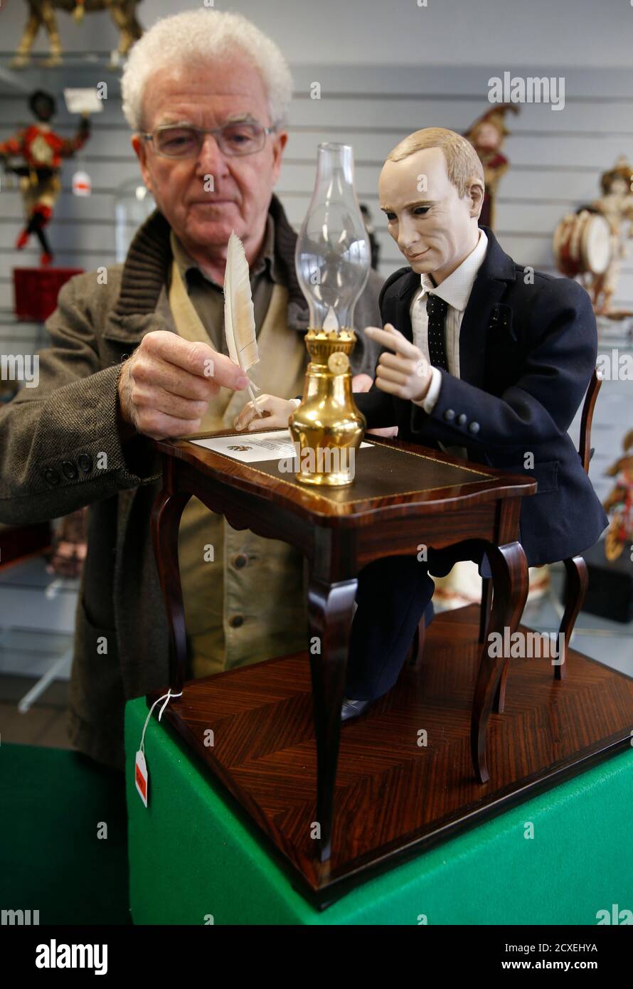 Uwe Breker, the world's leading auctioneer of Technical Antiques fixes the quill pen to a contemporary Musical Automaton depicting Russian President Vladimir Putin, in Cologne October 27, 2014. Inspired by Gustave Vichy's automaton 'Pierrot Ecrivain' of 1895, French artist Christian Baily of Paris portrays Putin signing the 'Treaty of Acceptance of the Republic Crimea into the Russian Federation' from March 18, 2014. The starting price of the automaton in the November 15 auction in Cologne, will be at 18,000 euros (US $ 22,900).  Putin is portrayed with blue glass eyes and molded hair, seated  Stock Photo