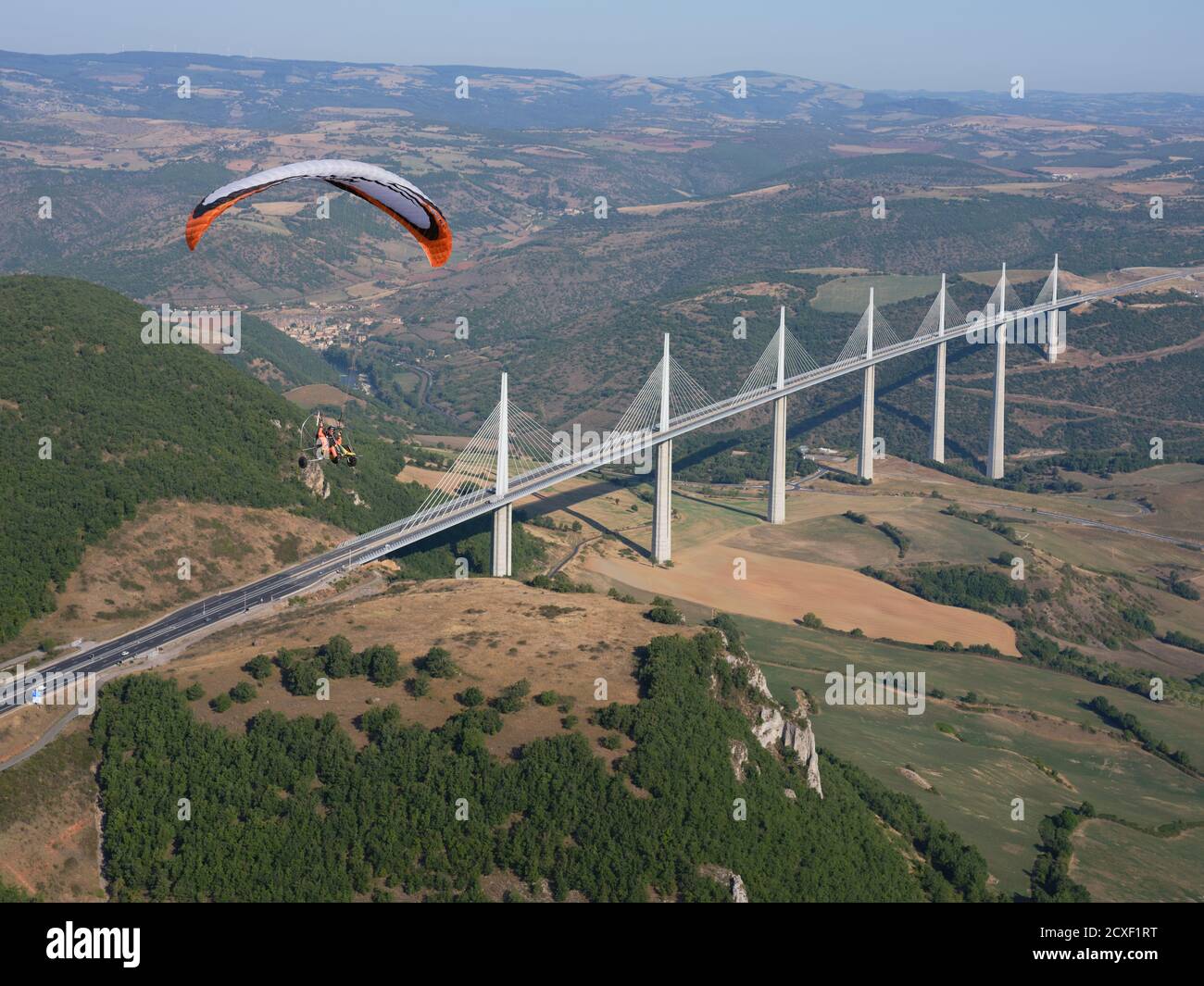 AIR-TO-AIR VIEW. Paramotor flying in the vicinity of the Millau Viaduct, the world's tallest bridge as of 2020. Millau, Tarn Valley, Aveyron, France. Stock Photo