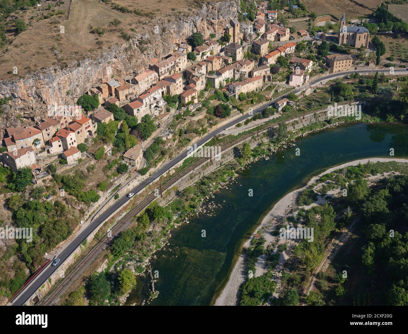 AERIAL VIEW. Picturesque village situated at the foot of a cliff and overlooking the Tarn River. Peyre, Comprégnac, Aveyron, Occitanie, France. Stock Photo