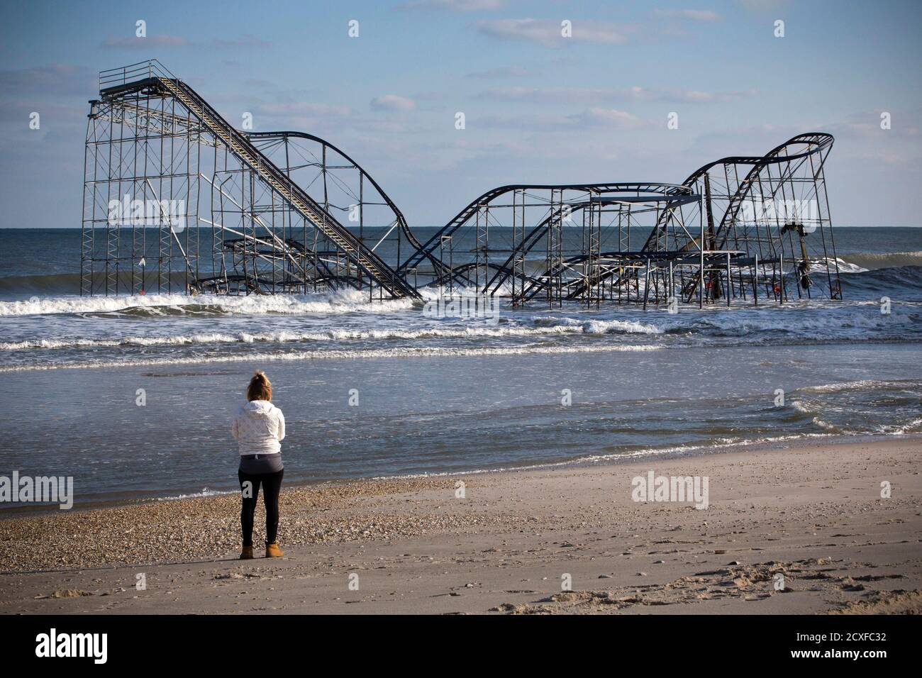 A woman looks at a roller coaster sitting in the ocean, when the boardwalk  it was built upon collapsed during Hurricane Sandy, in Seaside Heights, New  Jersey November 28, 2012. The storm