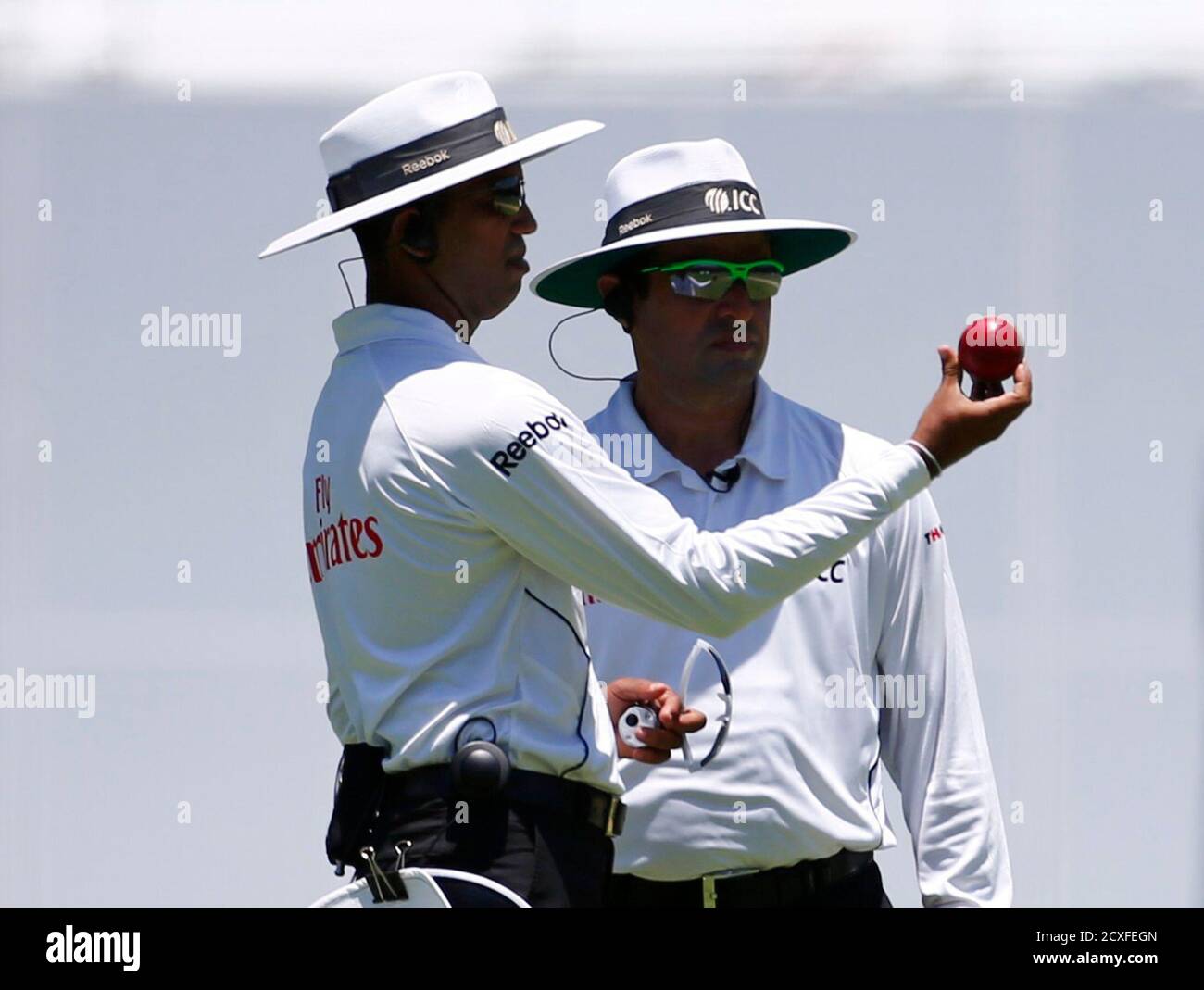 Umpires Kumar Dharmasena (L) of Sri Lanka and Aleem Dar of Pakistan inspect the ball before changing it during the first day's play of the first Ashes test cricket match between Australia and England in Brisbane November 21, 2013. REUTERS/David Gray (AUSTRALIA - Tags: SPORT CRICKET) Stock Photo