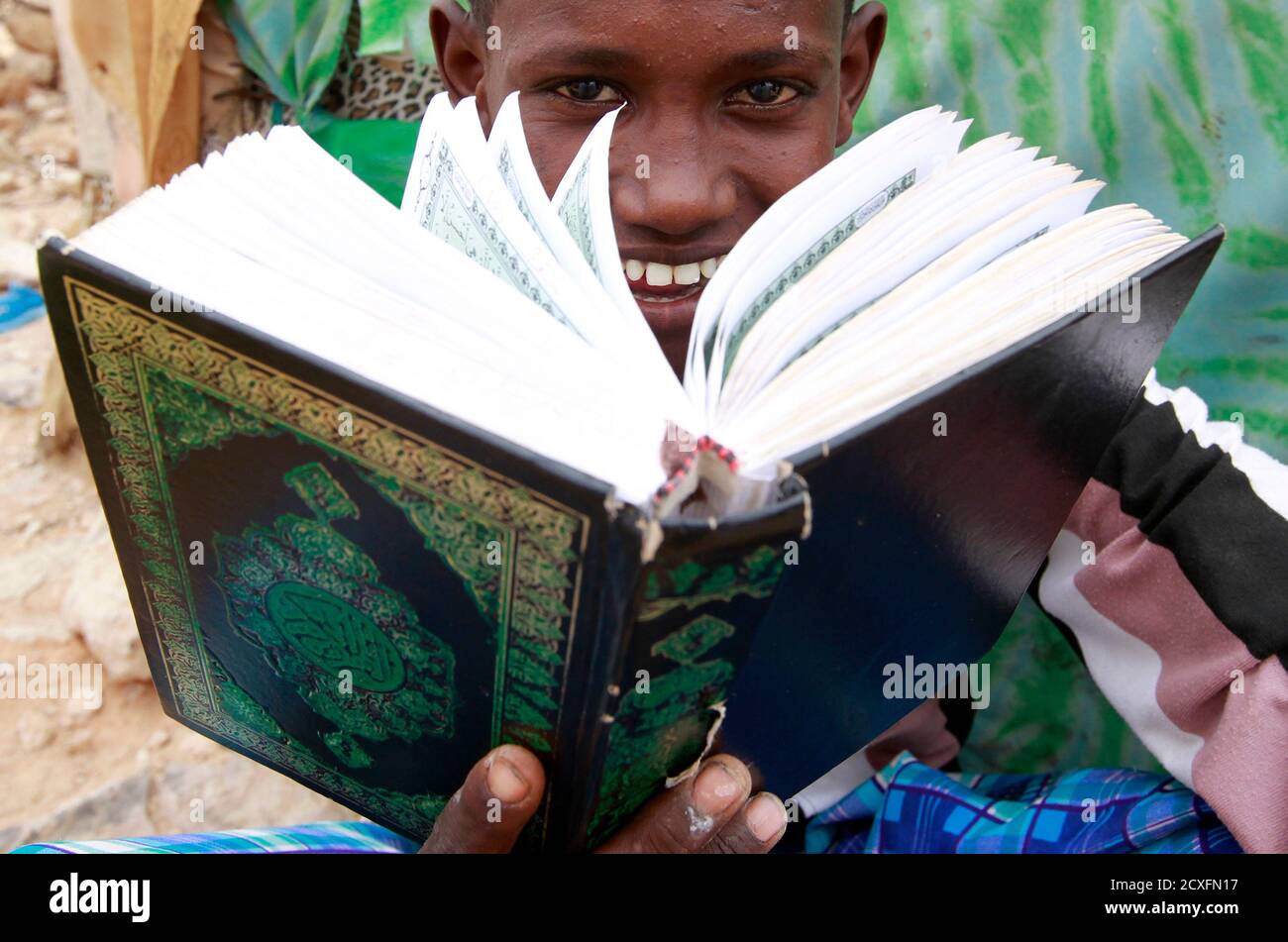 An internally displaced Somali boy reads the Koran as he attends classes at a Muslim Madrasah (Islamic school) outside a makeshift classroom at the Halabokhad IDP settlement in Galkayo, northwest of Somalia's capital Mogadishu, July 20, 2011. Galkayo hosts over 60,000 internally displaced Somalis in 21 settlements and there are always new arrivals due to the prolonged drought. The United Nations on Wednesday declared famine in two regions of southern Somalia, and warned that this could spread further within two months in the war-ravaged Horn of Africa country unless donors step in. REUTERS/Tho Stock Photo