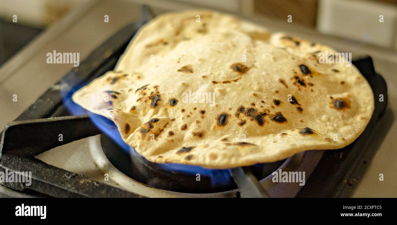 Wheat chapati or roti cooked on fire using a gas stove Stock Photo Alamy