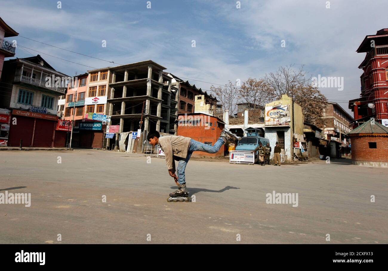 A Kashmiri boy roller skates past Indian policemen standing guard during a curfew in Srinagar February 12, 2013. India hanged Mohammad Afzal Guru, a Kashmiri man, on Saturday for an attack on the country's parliament in 2001, sparking clashes in Kashmir between protesters and police. Security forces had imposed a curfew in parts of Kashmir and ordered people off the streets. REUTERS/Danish Ismail (INDIAN-ADMINISTERED KASHMIR - Tags: POLITICS) Stock Photo