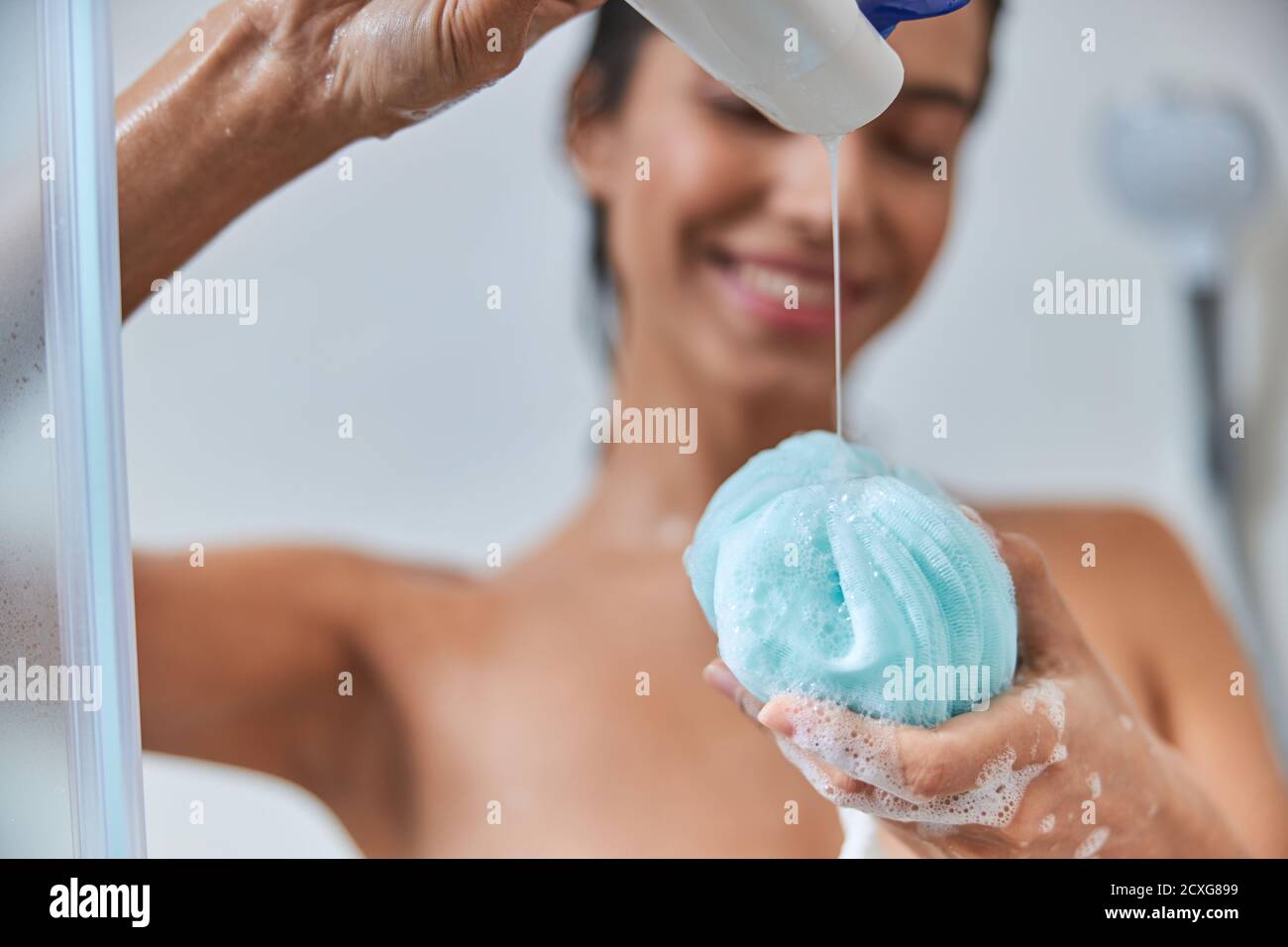 Cheerful young woman pouring shower gel on bath loofah Stock Photo Alamy