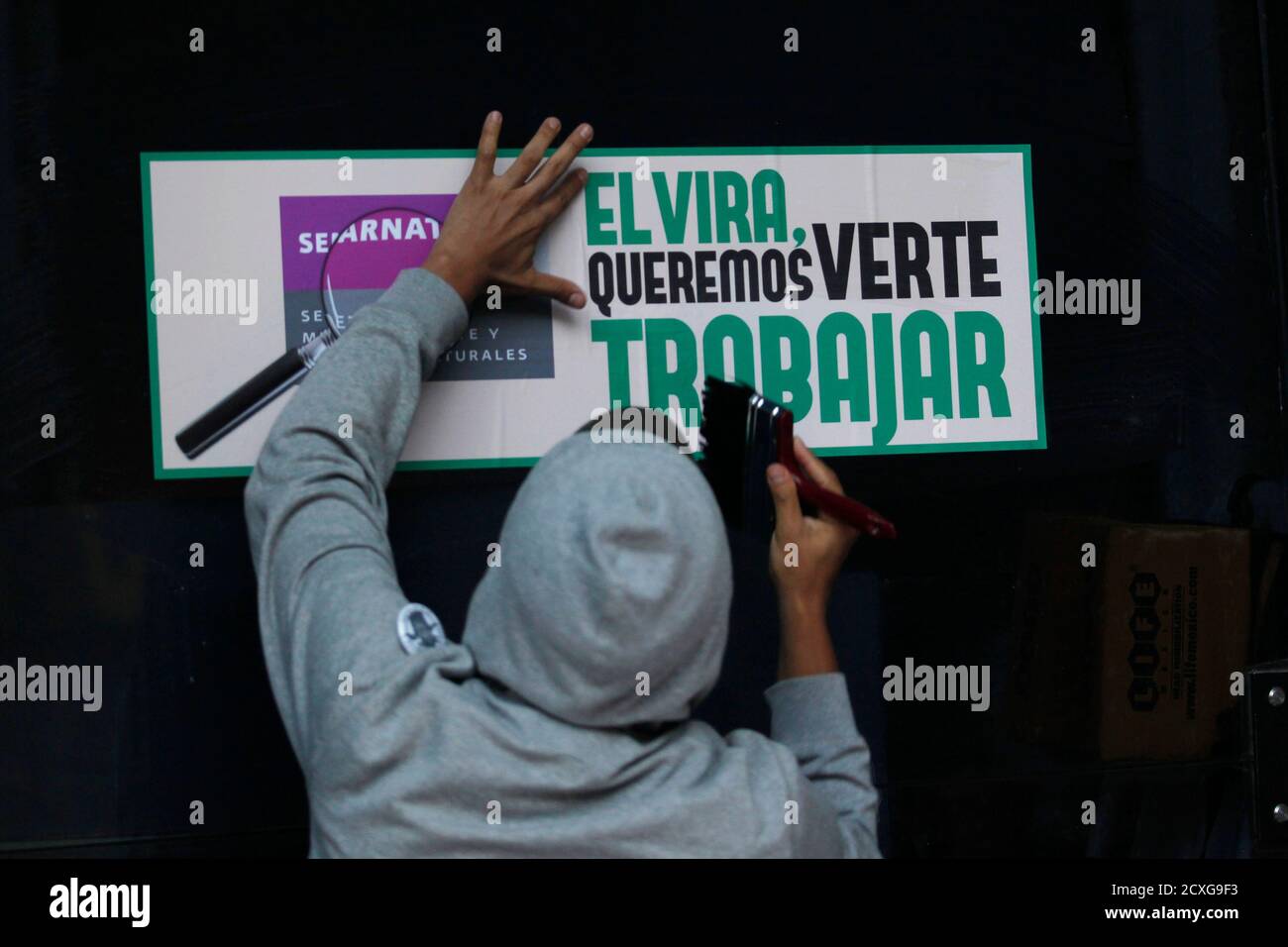 A Greenpeace activist pastes a poster in protest against the cultivation of transgenic maize outside the SEMARNAT (Secretary of Environment and Natural Resources) building in Mexico City June 5, 2012. The posters read, 'Elvira we want to see you work.' REUTERS/Edgard Garrido (MEXICO - Tags: ENVIRONMENT CIVIL UNREST AGRICULTURE) Stock Photo