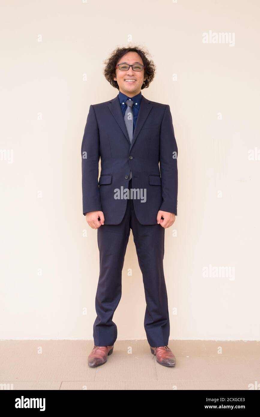 Full body shot of happy Japanese businessman in suit with eyeglasses ...