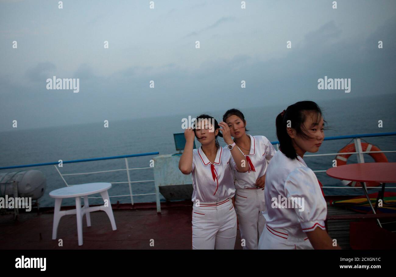 Workers of the Mangyongbyong cruise ship stand on the deck, near Mount Kumgang resort September 1, 2011. The North Korean state launched itself into the glitzy world of cruise tourism when about 130 passengers set sail from the rundown port of Rajin, near the China-Russia border, for the scenic Mount Kumgang resort near the South Korean border. Isolated North Korea's "state tourism bureau" has teamed up with a Chinese travel company to run the country's first ever cruise aboard an ageing 9,700 tonne vessel which once plied the waters off the east coast of the divided peninsula shuttling passen Stock Photo