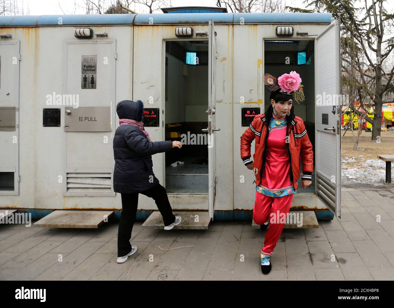 A male folk artist (R) dressed as a traditional Chinese woman walks out of a mobile toilet ahead of a performance at a Spring Festival Temple Fair on the fifth day of the Chinese Lunar New Year at Longtan Park in Beijing February 14, 2013. The Lunar New Year, or Spring Festival, began on February 10 and marks the start of the Year of the Snake, according to the Chinese zodiac. REUTERS/Jason Lee (CHINA - Tags: SOCIETY ANNIVERSARY) Stock Photo