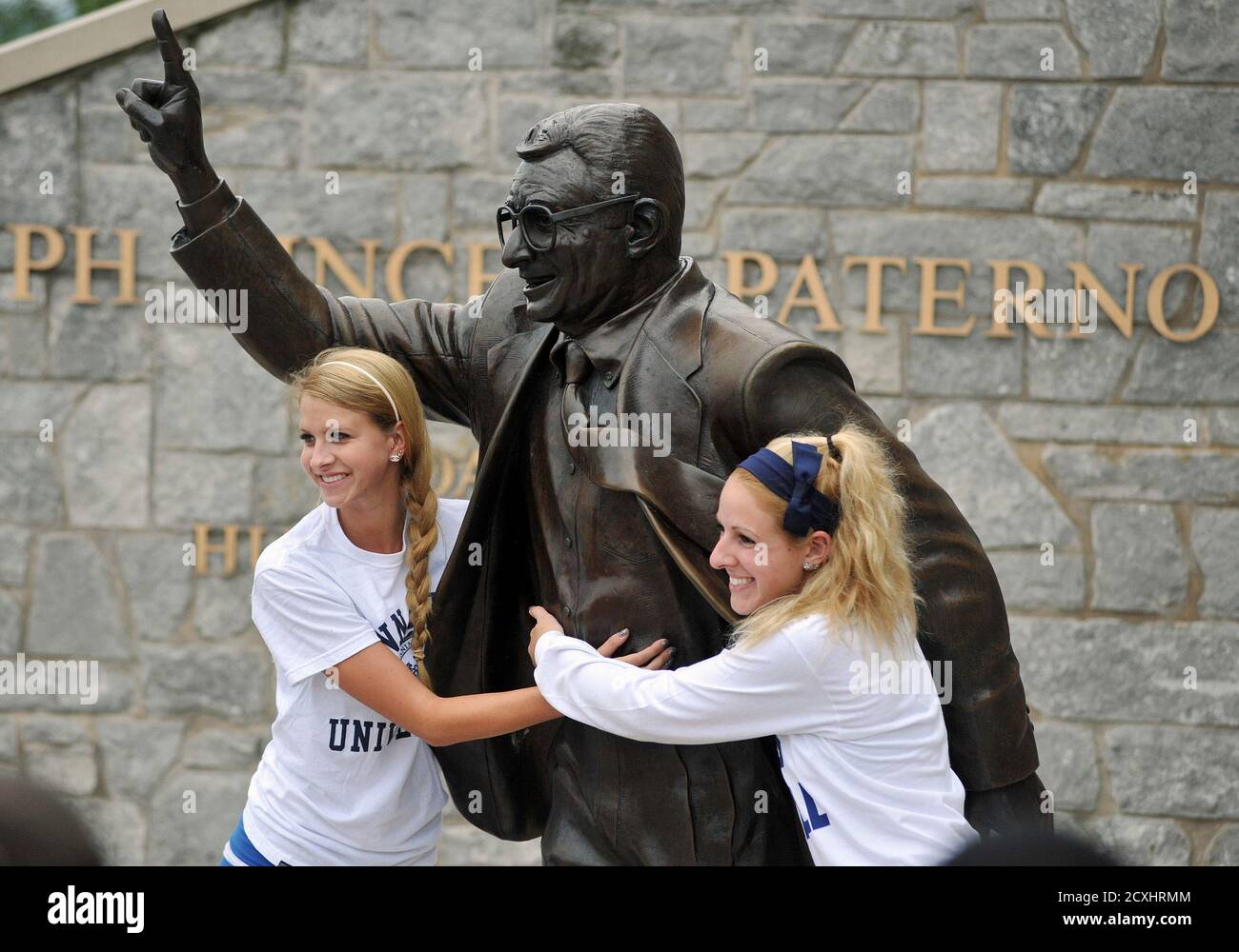 Penn State freshmen Caroline Vink (L) from Kutztown and Alexandra Brennan from Hazleton hug the Joe Paterno statue outside Beaver Stadium in State College, Pennsylvania, July 20, 2012. Penn State leaders acknowledged that the seven-foot (2.1-metre) statue of the late Paterno had become 'a source of division' at the school after Jerry Sandusky, Paterno's former assistant coach, was convicted in June of sexually abusing 10 boys over 15 years. The statue was removed on July 22. Picture taken July 20, 2012. REUTERS/Pat Little (UNITED STATES - Tags: SPORT FOOTBALL EDUCATION CRIME LAW) Stock Photo
