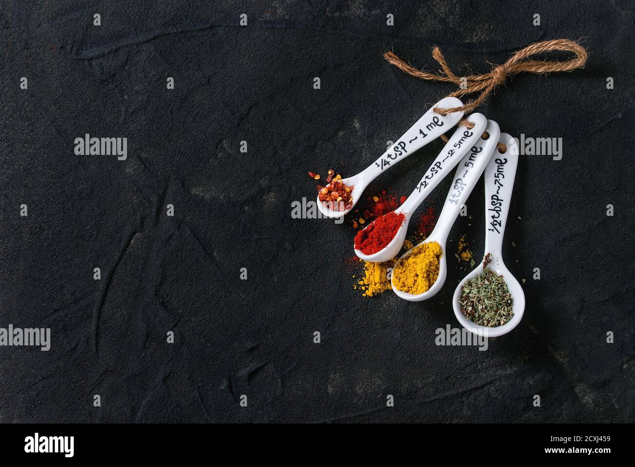 https://c8.alamy.com/comp/2CXJ459/assortment-of-ground-colorful-spices-in-white-different-ceramic-measuring-spoons-over-black-textured-background-with-copy-space-top-view-2CXJ459.jpg