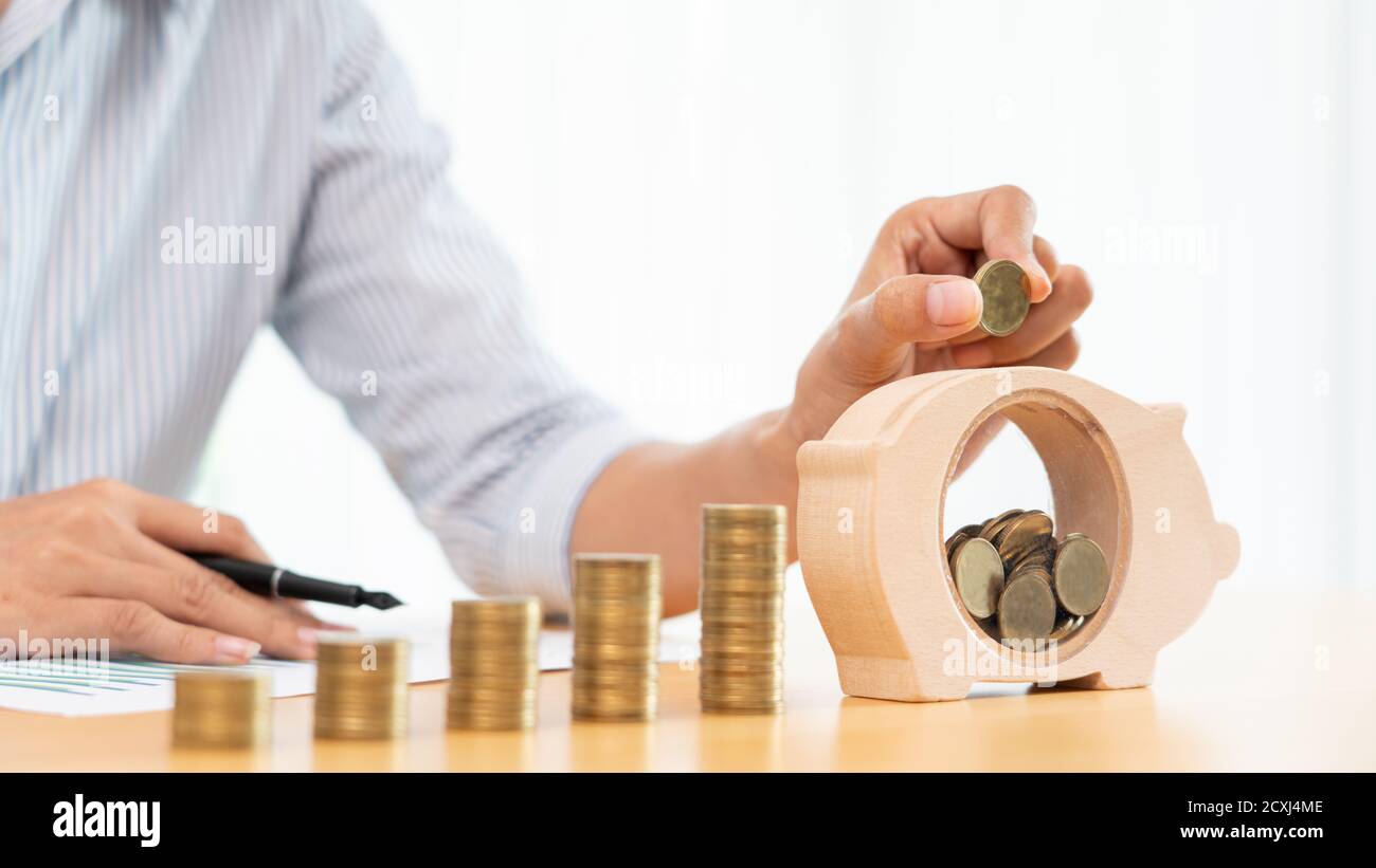 woman hand putting money coin into piggy bank with step of growing ...