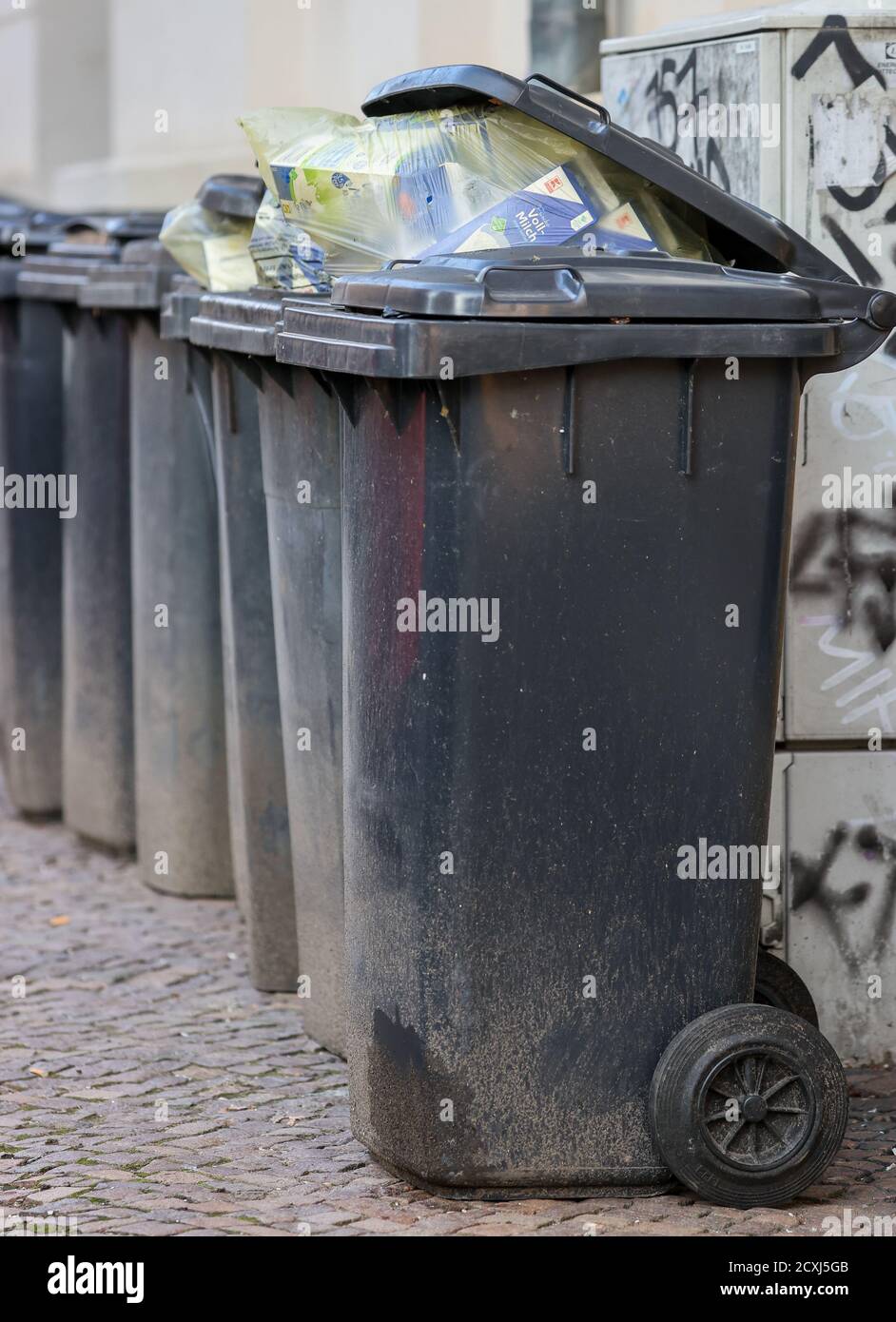 Leipzig, Germany. 01st Oct, 2020. Several full dustbins for residual waste,  which are also filled incorrectly, are located on a house wall. The trade  union Verdi is calling on employees in waste