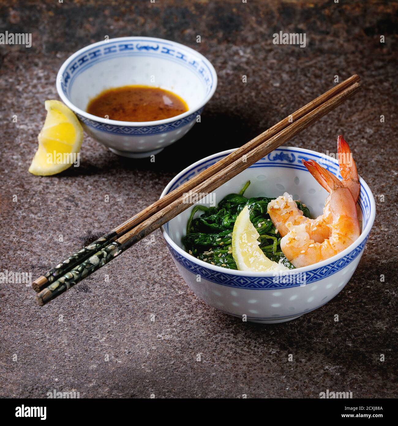 Chinese bowls with Cooked spinach and fried shrimps prawns with lemon