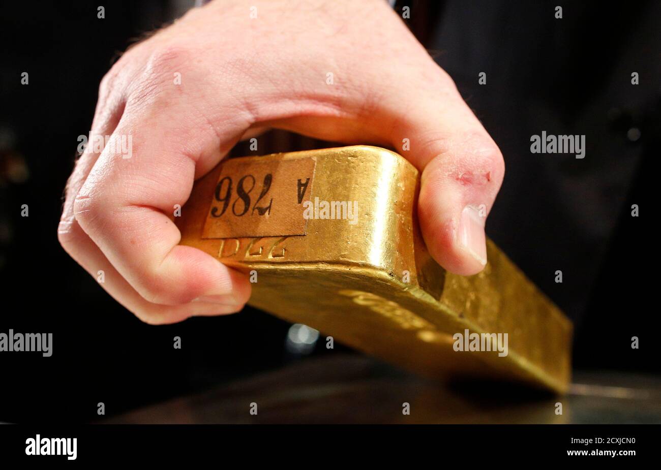 An employee of Deutsche Bundesbank picks up a gold bar during a news  conference in Frankfurt January 16, 2013. Germany's Bundesbank plans to  bring home some of its gold reserves stored in