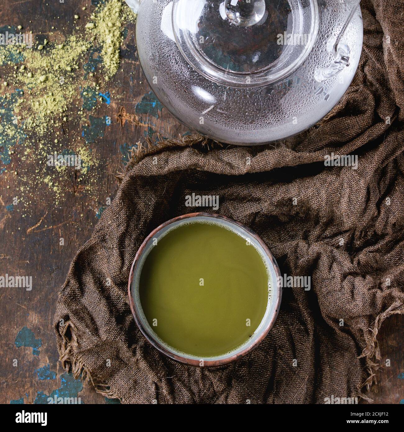 Ceramic cup of green matcha tea with glass teapot with hot water on wet ...
