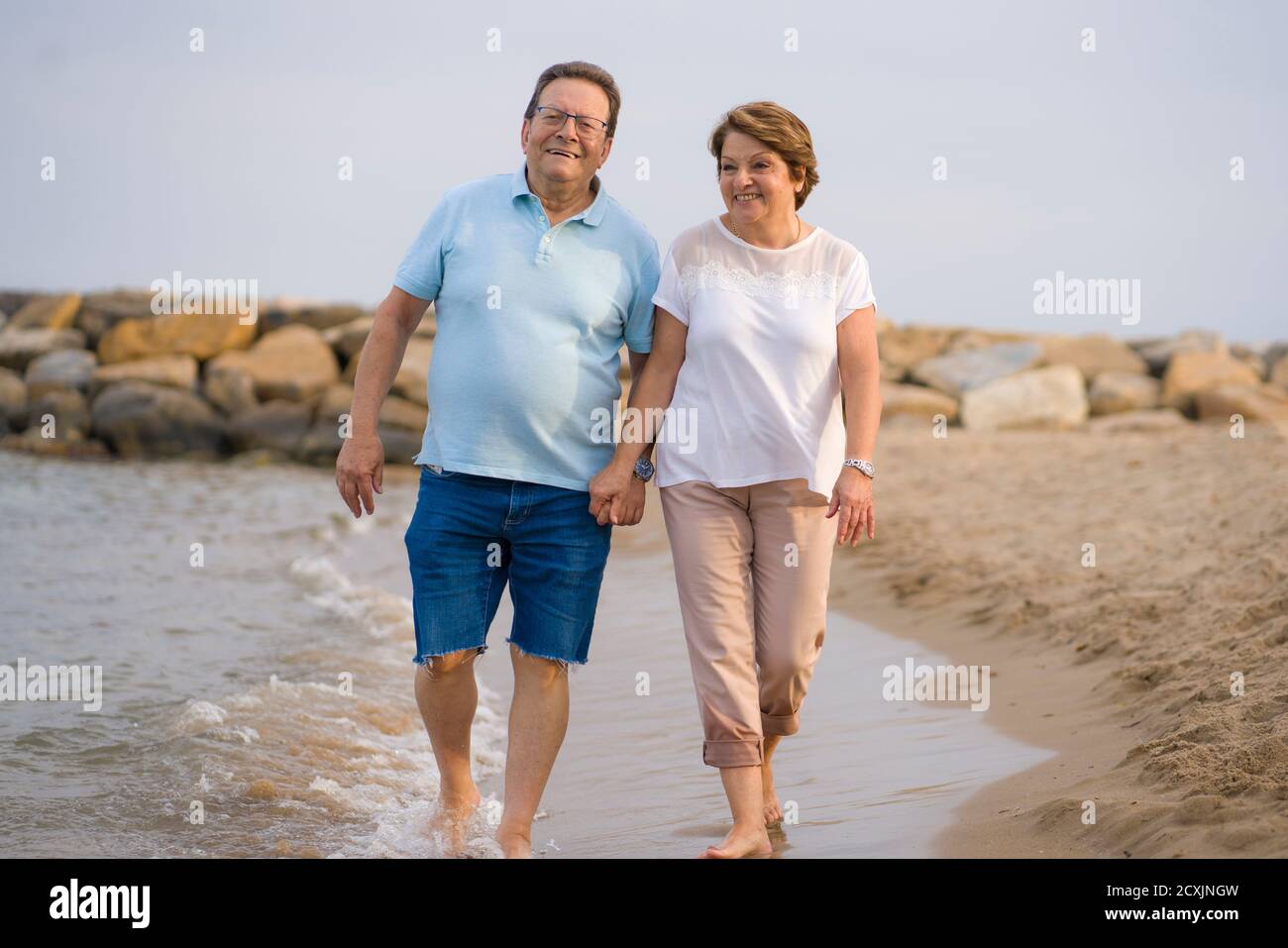happy retired mature couple walking on the beach pensioner woman and
