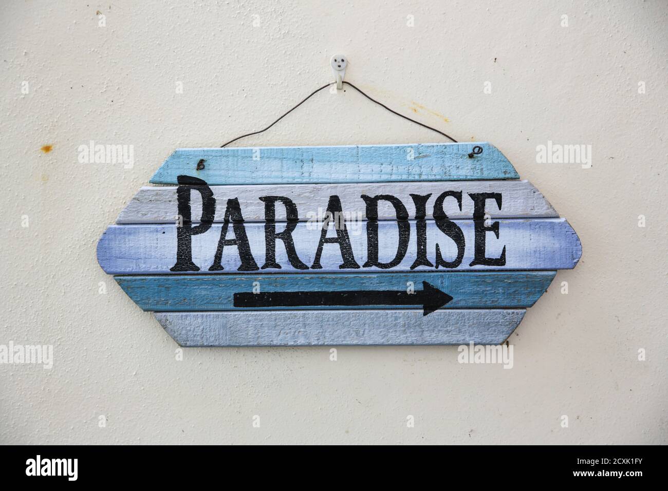 weathered wooden sign with an arrow pointing right to paradise Stock Photo