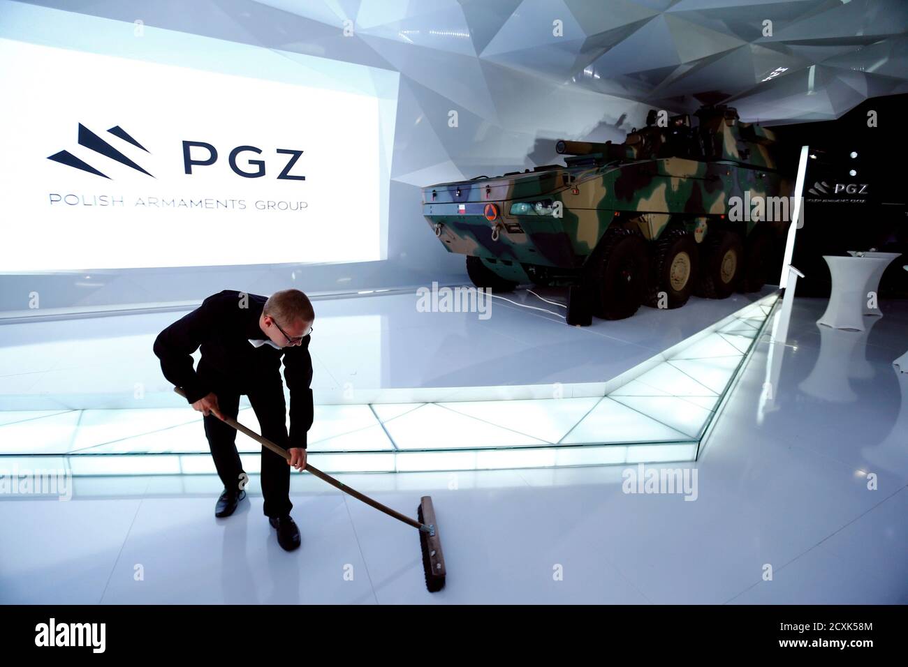 A man cleans the floor near an Armored Modular Vehicle 'Rosomak' at the Polish Arms Group (PGZ) stand at an international military fair in Kielce, southern Poland September 2, 2014. Poland on Wednesday brought small defence manufacturers into a consortium big enough to bid, alongside foreign majors, for a share of the country's $40 billion military modernisation pot. The PGZ, set to comprise over 30 companies ranging from a shipyard to a high-tech graphene manufacturer, will allow the country's fragmented industry to compete for state tenders against large foreign companies. Picture taken on S Stock Photo