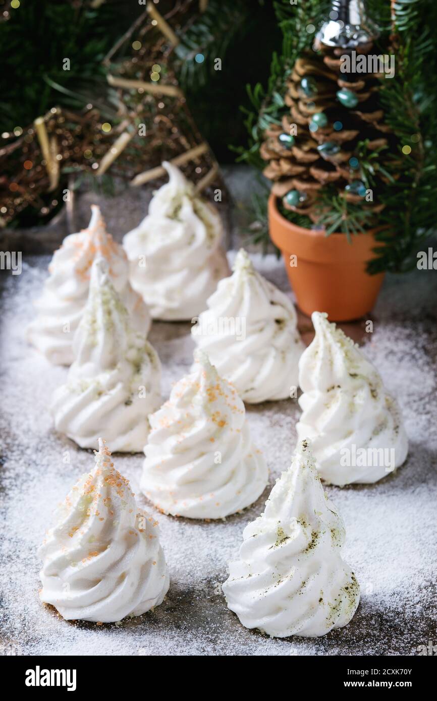 Homemade white french meringue as Christmas fir tree decorated by colored sugar and matcha tee over powdered old metal background with holiday decorat Stock Photo