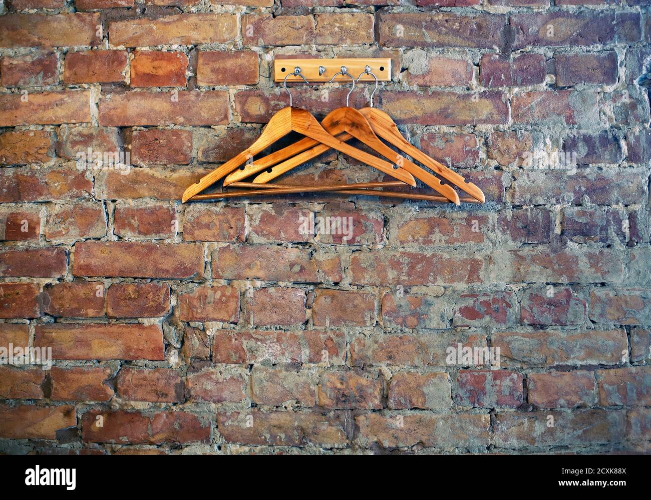 Bricks wall background with rack and wooden clothes hangers, cafe restaurant wardrobe corner, loft style Stock Photo