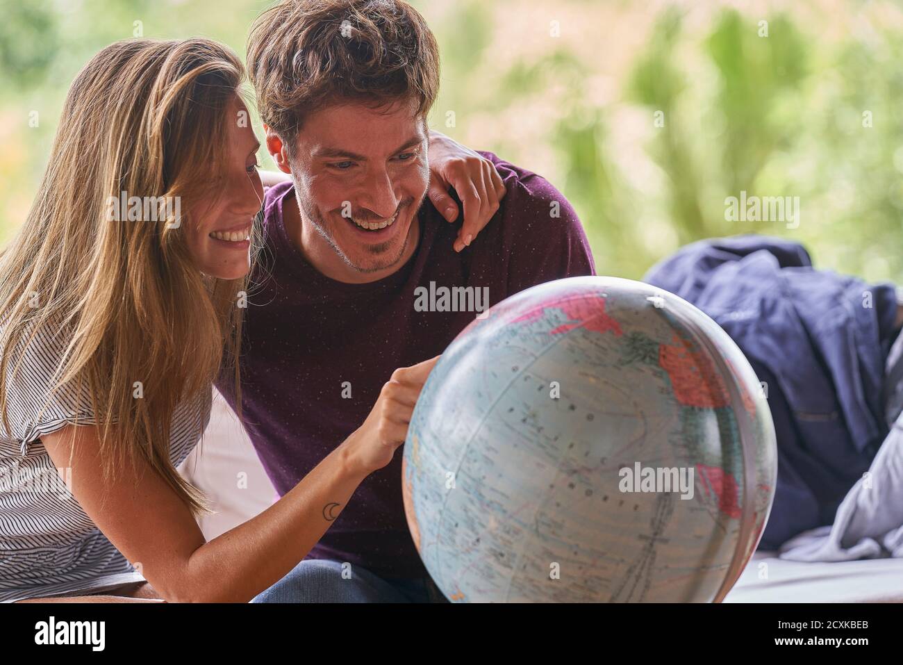 Young couple exploring world globe while sitting on sofa Stock Photo