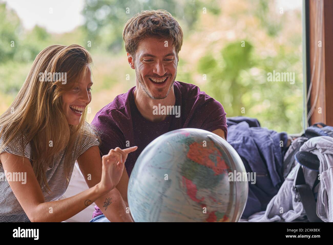 Young couple exploring world globe while sitting on sofa Stock Photo