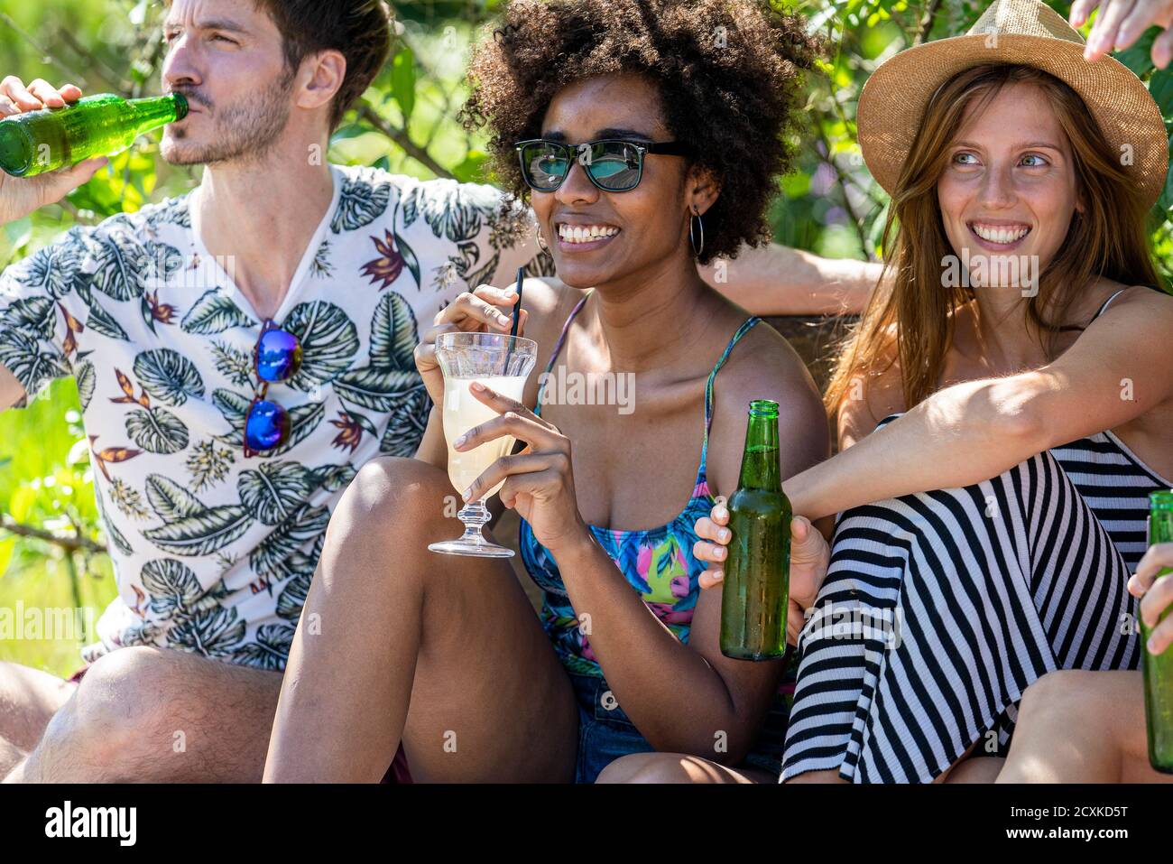 Young friends enjoying drinks at poolside Stock Photo
